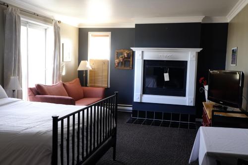 a bedroom with a bed and a living room with a fireplace at Auberge La Camarine in Beaupré