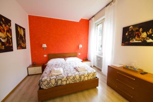 um quarto com uma cama com uma parede laranja em Luci A San Siro em Milão
