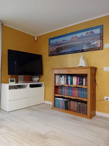 a living room with a flat screen tv and a book shelf at Villa Botton d'Oro Villa al lago in Lagolo di Calavino
