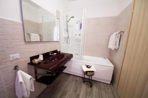 uma casa de banho com um lavatório, uma banheira e um espelho. em Luci A San Siro em Milão
