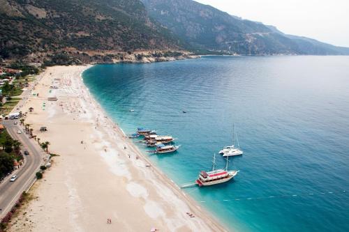 a group of boats in the water on a beach at London Hotel in Oludeniz