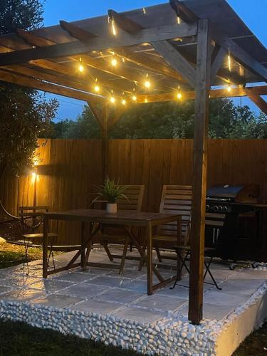 a wooden pergola with a picnic table and lights at Ellie's Eco Private Glamping and Spa in Nea Kalikratia