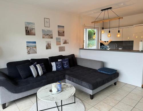 a living room with a black couch and a table at Ankerplatz - gemütliches Ferienhaus mit Garten und Terrasse für die große Familie in Grömitz