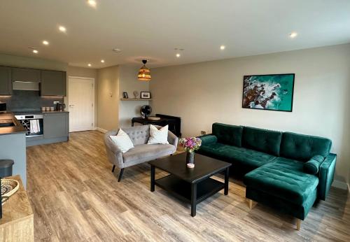 a living room with a green couch and a table at Raleigh Waterside apartment - The Barbican, Plymouth in Plymouth