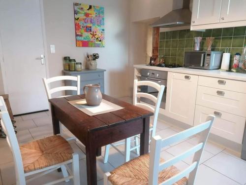 - une cuisine avec une table en bois et des chaises blanches dans l'établissement maison au cœur du triangle d'or, à Cestayrols