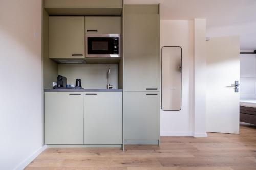 a kitchen with white cabinets and a refrigerator at BB aan de kapel in Roermond