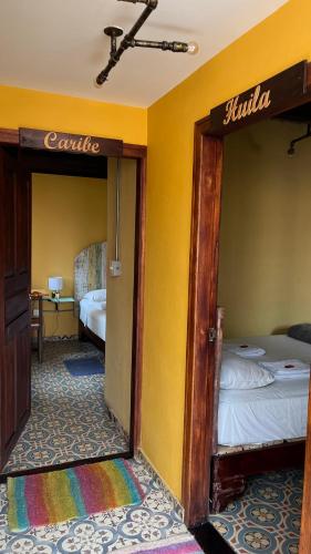 a room with two beds in a room with yellow walls at Hostal Casa Astromelia in Bogotá
