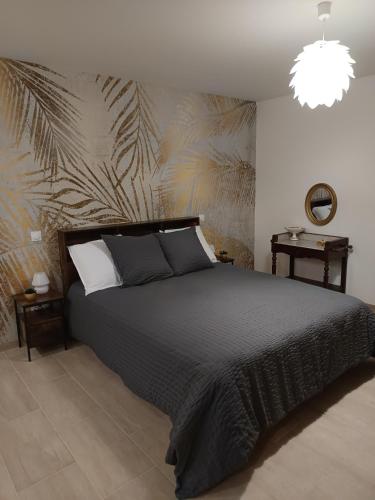 une chambre avec un lit noir avec un papier peint en feuille de palmier dans l'établissement L'atelier Détente et Spa, à Caudrot