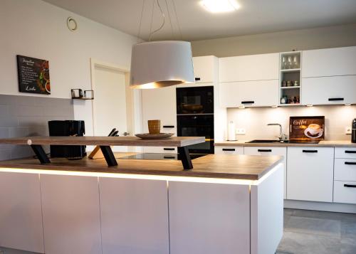 a kitchen with white cabinets and a wooden table at HeideFunHaus 2 in Neuenkirchen