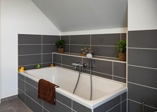 a bath tub in a bathroom with gray tiles at HeideFunHaus 2 in Neuenkirchen