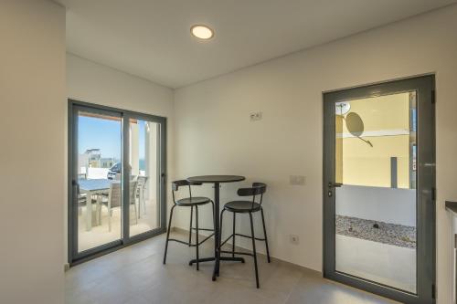 a dining room with a table and two stools at Silver Coast Beach Villa-Casa de Luxo com Piscina e Vista Mar in Lourinhã