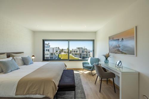 a bedroom with a bed and a desk and a window at Silver Coast Beach Villa-Casa de Luxo com Piscina e Vista Mar in Lourinhã