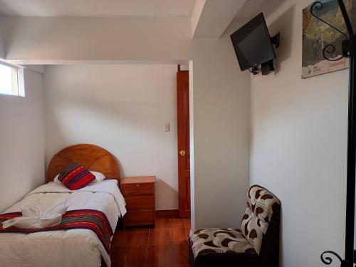una camera con letto, sedia e TV di Hotel TIKA AYNA Cerca a la plaza de Armas CUSCO a Cuzco