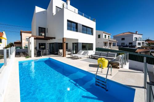 a villa with a swimming pool in front of a house at Silver Coast Beach Villa-Casa de Luxo com Piscina e Vista Mar in Lourinhã