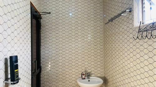 a bathroom with a sink and a white tiled wall at Maasai Hostel Tanzania in Arusha