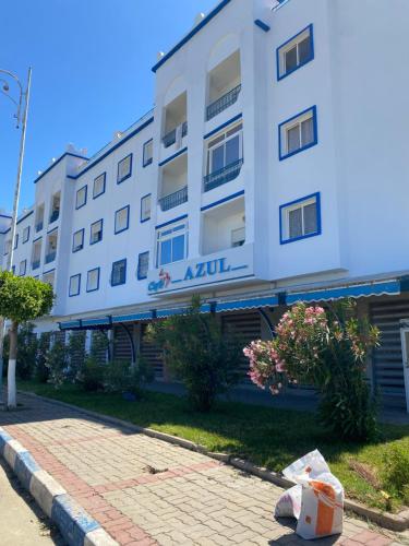 a white building with a sidewalk in front of it at Résidence riad sofia in Martil