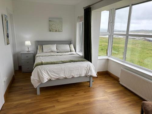 a bedroom with a bed and two windows at Cruit Island Holiday Rent in Cruit