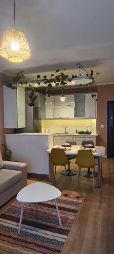a living room with tables and chairs and a kitchen at LA Comfy AP in Sarandë