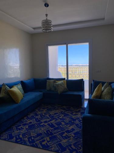a living room with a blue couch and a large window at Résidence riad sofia in Martil