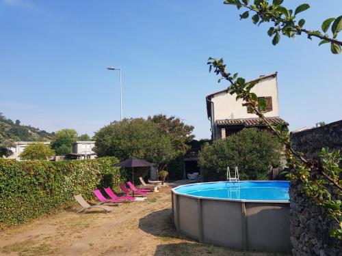 une piscine avec des chaises roses à côté d'une maison dans l'établissement Maison avec piscine, à Aubenas