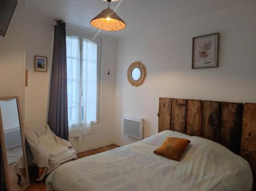 a bedroom with a bed with a wooden headboard and a window at T2 Coeur d' Argelès-Gazost, tout à pied in Argelès-Gazost