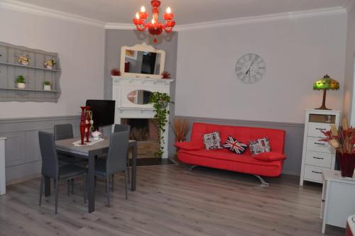 a living room with a table and a red couch at Casetta Valderoa Fiumicino in Fiumicino