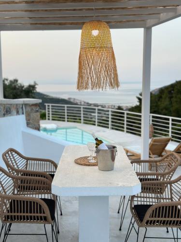 a white table with chairs and a chandelier at Villa Koukounaria in Skopelos Town