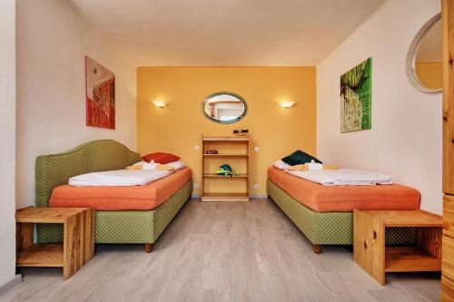 two beds in a room with two chairs and a mirror at Ferienwohnungen Theresienhof in Ledenitzen