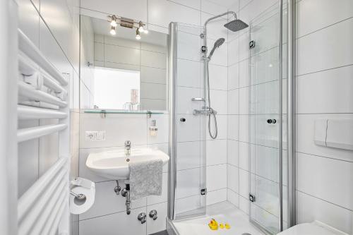 a white bathroom with a shower and a sink at Ferienwohnungen Theresienhof in Ledenitzen