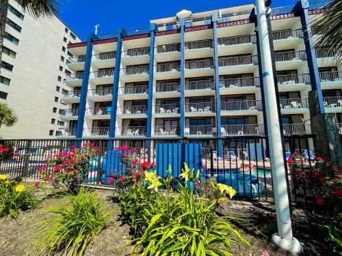 an apartment building with flowers in front of a fence at Grande Shores Ocean Resorts Condominiums in Myrtle Beach