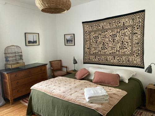 a bedroom with a bed with a tapestry on the wall at Grande maison - village de Noyers - 5 chambres in Noyers-sur-Serein