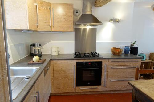 une cuisine avec un évier et une cuisinière four supérieur dans l'établissement Grande maison de village 200 m2 calme tout confort, à Gréolières