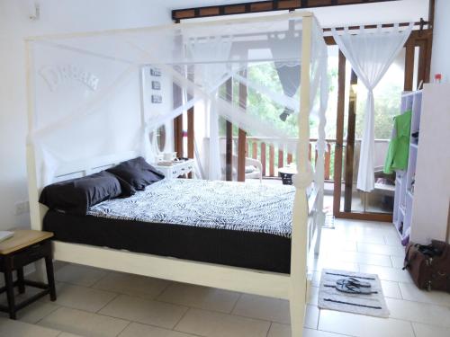 a bedroom with a canopy bed and a balcony at Restful Beach Front studio-Diani in Diani Beach