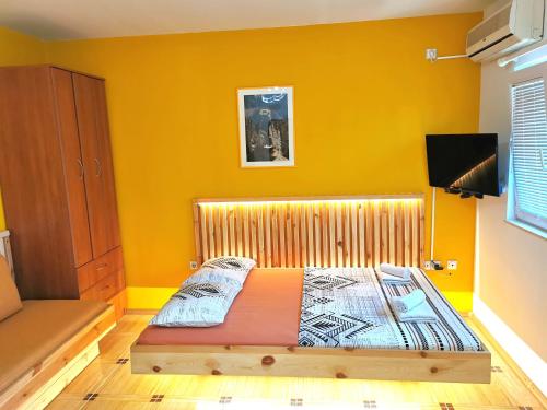 a bedroom with a wooden bed in a yellow room at Durakovic Apartments in Herceg-Novi
