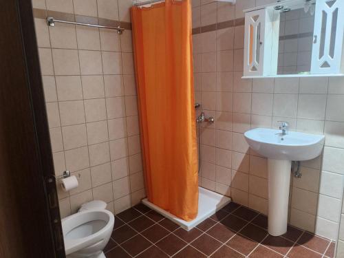 an orange shower curtain in a bathroom with a toilet and sink at Angel Rooms in Yiofirákia