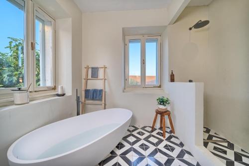 a bathroom with a white tub and a black and white floor at Hvar luxury Villa and pool with view in heart of Stari Grad in Stari Grad