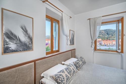 a bedroom with a bed and two windows at Hvar luxury Villa and pool with view in heart of Stari Grad in Stari Grad