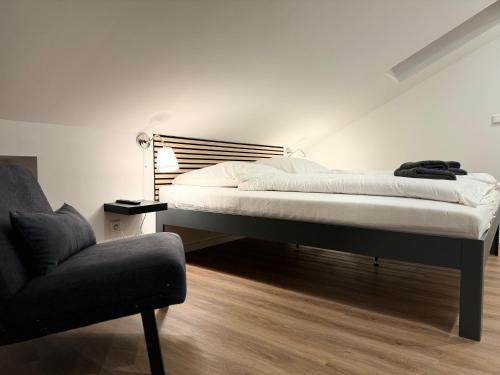 a bed in a room with a chair and a couch at Ankerplatz in Tönning