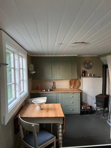 a kitchen with green cabinets and a table with a bowl on it at Koselig hytte på eget tun med varmtvanns utedusj in Ås