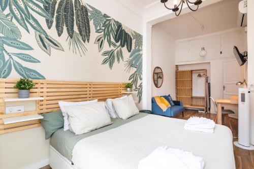 a bedroom with a large white bed with leaves painted on the wall at Mestalla River Apartment in Valencia