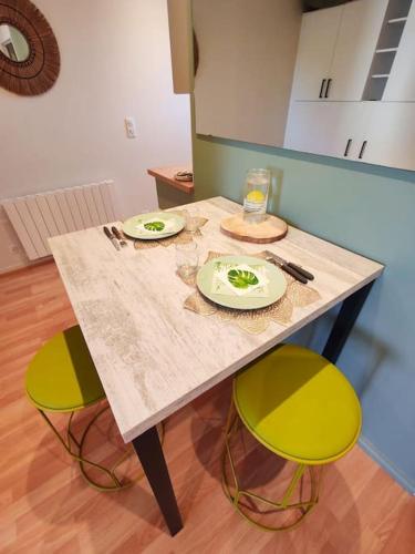 une table avec deux assiettes et deux chaises jaunes dans l'établissement Grand studio face mer, à Saint-Georges-de-Didonne