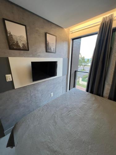 a bedroom with a large bed and a tv on a wall at Loft Luxo para 4 pessoas vista mar in Cabedelo