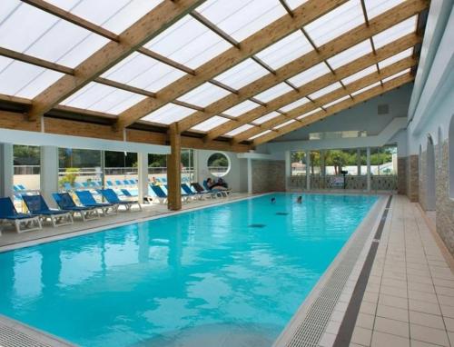 une piscine avec des chaises bleues et un plafond dans l'établissement Mobil-Home 6-8 personnes, à Saint-Jean-de-Monts