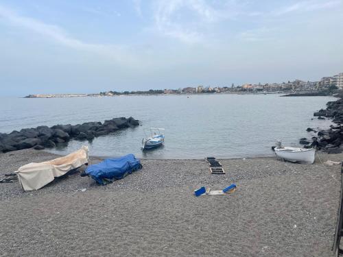 a beach with a boat and a tent and two boats at MARIDDA-experience rooms- in Giardini Naxos