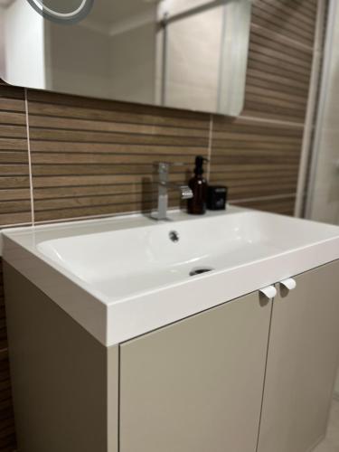 une salle de bain avec un lavabo blanc et un miroir dans l'établissement Duplex raffiné, élégant & climatisé - La MEZZ, à Nîmes