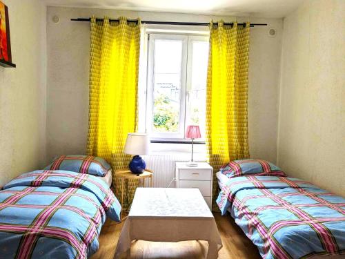 two twin beds in a room with yellow curtains at Plein centre de Visé in Visé