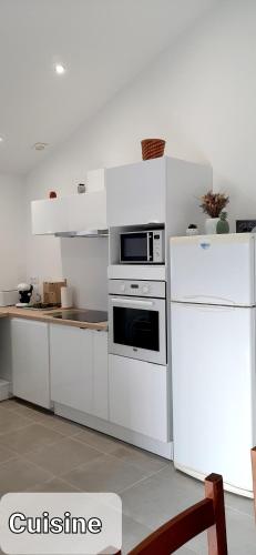 Il comprend une cuisine équipée d'appareils électroménagers blancs et d'un réfrigérateur blanc. dans l'établissement Appartement cosy 4 personnes, à Benesse-lez Dax