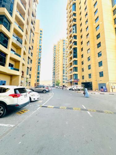 a street with parked cars and tall buildings at Elite Class Furnished Room in Ajman 