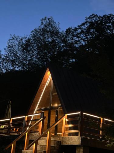 a cabin with lights on the side of it at night at Valea Mosului - Cozy A Frame in Petroşani