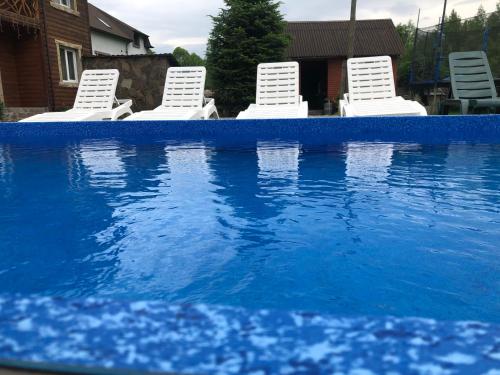 a group of white chairs and a swimming pool at Cottage Zhelikhovskykh in Tatariv